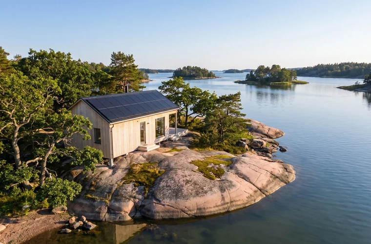 Hus i Blekinge skärgård med solceller på taket, lövträd och havet i bakgrunden